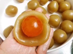 取一份莲蓉拍扁包入一整颗咸蛋黄