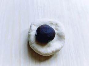 将剩下的面团分割成等份的小面团，醒5分钟，取一小块面团，放上豆沙馅，包起来，收口捏紧。依次做完！