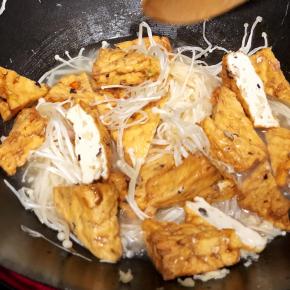 加入菜豆腐和金针菇翻炒片刻，加入少许水，盖上锅盖焖煮一会儿