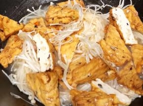 加入菜豆腐和金针菇翻炒片刻，加入少许水，盖上锅盖焖煮一会儿
