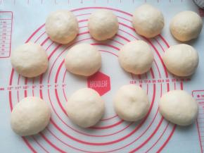 把发酵好的面团倒在台面上。轻拍排气，然平均分割成12分。可以根据自己烤盘的大小，来决定分成多少份。把分割好的面团分成12份，滚圆松弛5分钟。