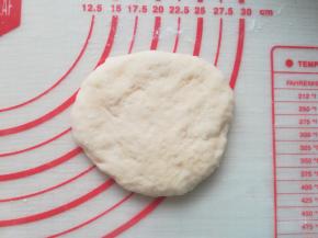 取一个面团按扁。拿起来的时候如果比较黏，可以借助刮板。