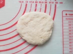 取一个面团按扁。拿起来的时候如果比较黏，可以借助刮板。
