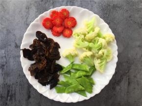 将胡萝卜切片，荷兰豆去筋切两半，黑木耳洗净拆小块。