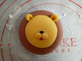 取2份0.5克黄色面团和一点点黑色面团做出狮子的鼻子部位，