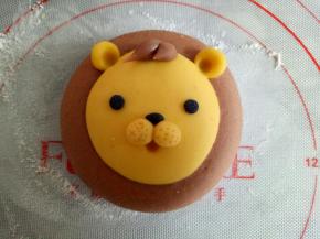 如图，将狮子的眼睛也做好，鼻子上用牙签扎一些小孔，用细一点的筷子扎出嘴巴来，适量可可面团做出狮子的鬃毛来(每个鬃毛大概0.5克)