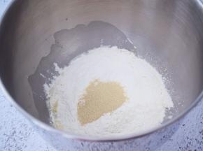 把材料除了黄油外，都放入和面桶，顺序为纯牛奶、鸡蛋液、糖和盐对角放，然后放面粉，酵母放最上面