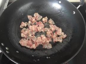 4、培根切成小块，放入炒锅小火煎出油和水份。这样做是为了防止披萨在烘烤的过程中产生过多的水分和油份而影响最后成品的口感。