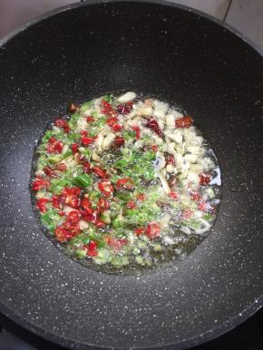 用煎臭豆腐的油，继续烧至七成热，放入蒜瓣，花椒，干辣椒，青红辣椒爆香。