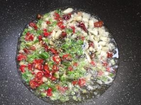 用煎臭豆腐的油，继续烧至七成热，放入蒜瓣，花椒，干辣椒，青红辣椒爆香。