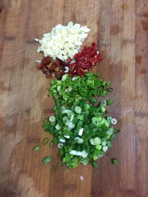 蒜瓣一个薄皮剁碎，干辣椒切成段，青红辣椒切成圈儿，葱切成葱花备用。