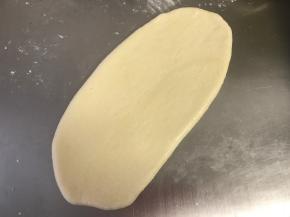 擀面的时候把光滑的一面放在下面，按扁、擀成椭圆形（大概20厘米长）。
