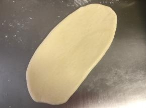 擀面的时候把光滑的一面放在下面，按扁、擀成椭圆形（大概20厘米长）。