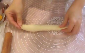 挤入一条馅料，上下两端不挤馅料，从没捻薄的那侧开始卷起，收口贴合。上下两端也捏合严实，成长条橄榄形。