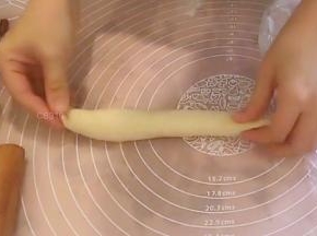 挤入一条馅料，上下两端不挤馅料，从没捻薄的那侧开始卷起，收口贴合。上下两端也捏合严实，成长条橄榄形。