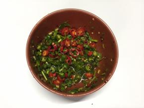 将青线椒、小红椒、香葱、香菜放入碗中，加入辣椒油、盐、白糖、鸡精、白醋、香油搅拌均匀成酱料汁
