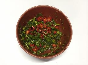 将青线椒、小红椒、香葱、香菜放入碗中，加入辣椒油、盐、白糖、鸡精、白醋、香油搅拌均匀成酱料汁
