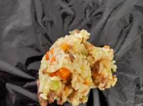 待炒饭稍微晾凉后，在桌面铺一张保鲜膜，放上适量炒饭。