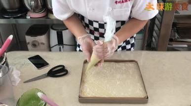 烤盘提前铺好油布或油纸，混合好的面糊倒入烤盘中用刮板刮平，表面撒上椰蓉，挤上香蕉卡士达酱。