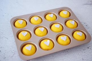 用纸剪出爱心的形状，然后把爱心放上面包生坯上