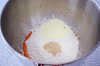 把材料除了黄油外，都放入和面桶，顺序为胡萝卜泥、鸡蛋、糖和盐对角放，然后放淳璀有机幼儿配方奶粉和面粉，酵母放最上面