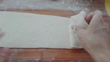 用手将窄的一端开始折卷起来。