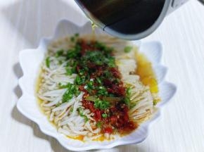 将蒸熟的金针菇取出,把切好的青椒撒在金针菇上面,再把烧热的油淋在上面。