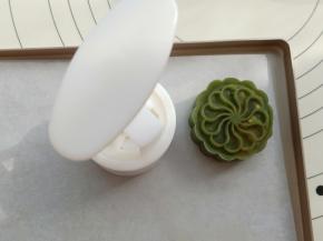 月饼模具撒点低粉，然后磕一下，把多余的粉磕出去，粉一定不要多。薄薄一层。把包好的桃山皮月饼放入模具中，然后在阳晨长方形牛扎糖烤盘上按出花纹。