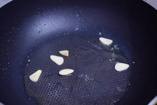 另起锅倒入适量的食用油烧热后，放入蒜片炒出香味