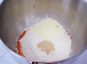 把材料除了黄油外，都放入和面桶，顺序为胡萝卜泥、鸡蛋、糖和盐对角放，然后放奶粉和面粉，酵母放最上面