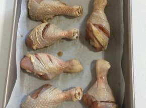 取一个深烤盘，铺上一层油纸（或锡纸），把腌制好的鸡腿放在烤盘里。