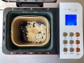 把蝶豆花水、糖、盐、高筋面粉和酵母放入柏翠面包机的面包桶中，启动和面程序，揉面15分钟。