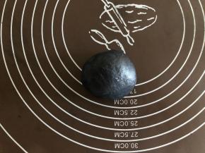 把大面团分出90克一个的小面团，揉进0.5克的竹炭粉，成为一个黑色的小面团。