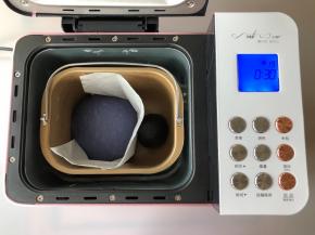 把两个颜色的面团揉圆，把面包桶的搅拌刀取出，把两个面团中间隔上烘焙纸，放入面包桶中进行发酵，选择发酵程序，设定30分钟。