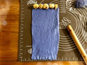 取大的蓝色面团，擀成和面包机内宽差不多的长方形，底边压薄，顶部摆上一排无花果干。