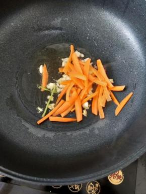 然后放入胡萝卜丝，快速翻炒均匀。
