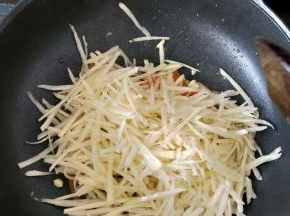 接着倒入沥水后的土豆丝，继续翻炒均匀。