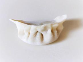 将饺子皮对折，再将两边捏紧，捏出皱褶，依次包完。