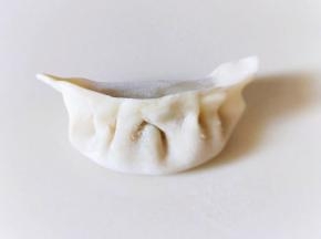 将饺子皮对折，再将两边捏紧，捏出皱褶，依次包完。