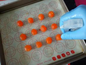 接下来处理蛋黄，我是把蛋黄一分为二用的，蛋黄有提前用油泡了3天，分开后的蛋黄稍微捏圆一点，喷点白酒，放入预热好的烤箱180度烤3分钟，出炉翻个面再烤3分钟