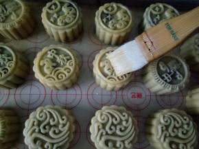 5分钟后烤箱不要关，拿出月饼来刷一层薄薄的蛋液，继续送入烤箱180度烤20分钟左右，注意看上色状态，月饼两侧腰身鼓起上色满意就可以出炉了