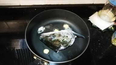 不粘锅里放入油、姜爆香，放入三文鱼头两边煎至金黄色