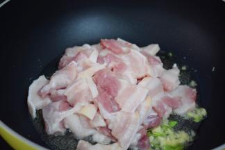 再放入五花肉，翻炒至变色