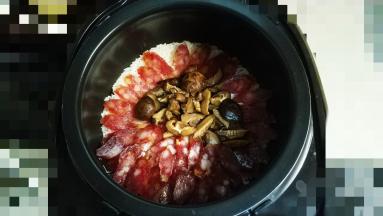等到饭煲出烟（蒸汽）放入腊肠和花菇至煮饭程序结束