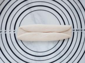 翻面后将面团90度旋转，再分别从1/4之处往上下方向折叠，并压紧。