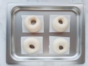 长条收成圆形，用擀开的那一部分包住另一边，收紧。把做好的贝果胚放到垫了油纸的烤盘里，在温暖处发酵30分钟。