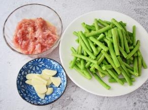 猪肉洗净切成薄片加入料酒、盐、味极鲜酱油、玉米淀粉、食用油抓匀腌制半小时，豇豆去掉头尾洗净切寸段，蒜切片
