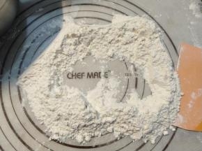 将余下的面粉倒在面板上，在面粉中间掏一个洞。