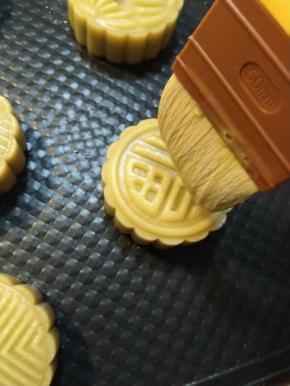 把一个鸡蛋跟一个蛋黄搅打均匀顺滑，用羊毛刷沾上少许，用羊毛刷的毛尖轻轻的快速的在压好的月饼表面刷上薄薄的2层。（全部刷完一次之后再从头开始刷第二遍）