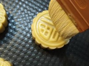 把一个鸡蛋跟一个蛋黄搅打均匀顺滑，用羊毛刷沾上少许，用羊毛刷的毛尖轻轻的快速的在压好的月饼表面刷上薄薄的2层。（全部刷完一次之后再从头开始刷第二遍）